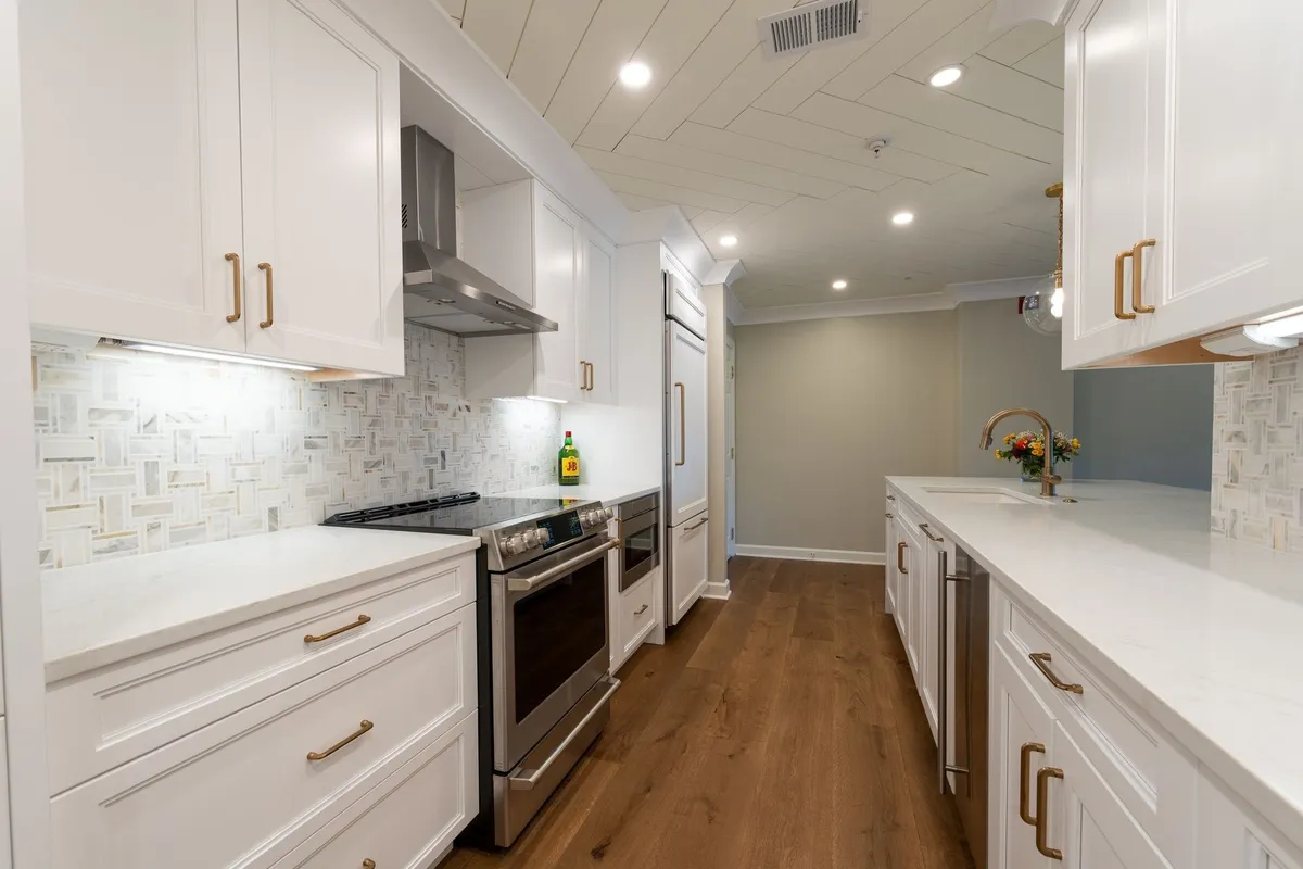 A modern kitchen with white cabinets and stainless steel appliances, reflecting custom home design choices.
