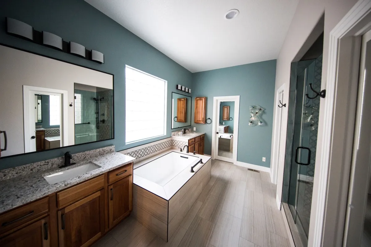 A spacious modern bathroom with a freestanding bathtub, wooden cabinets, and granite countertops.