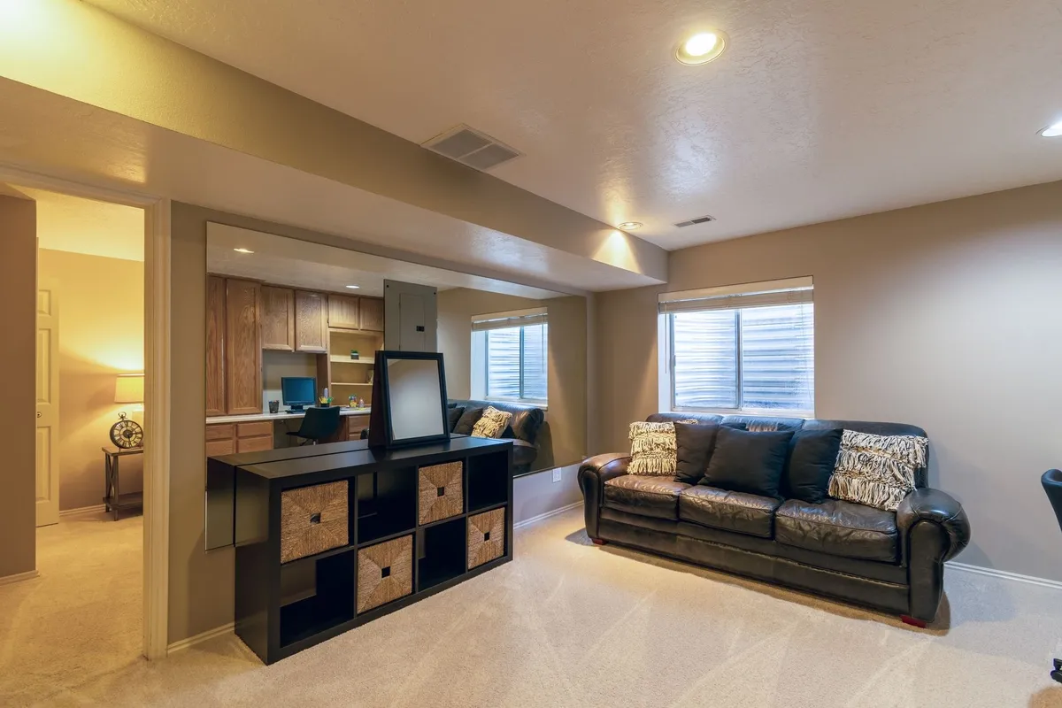 A cozy basement living room with a leather sofa and modern decor, showcasing a successful renovation.
